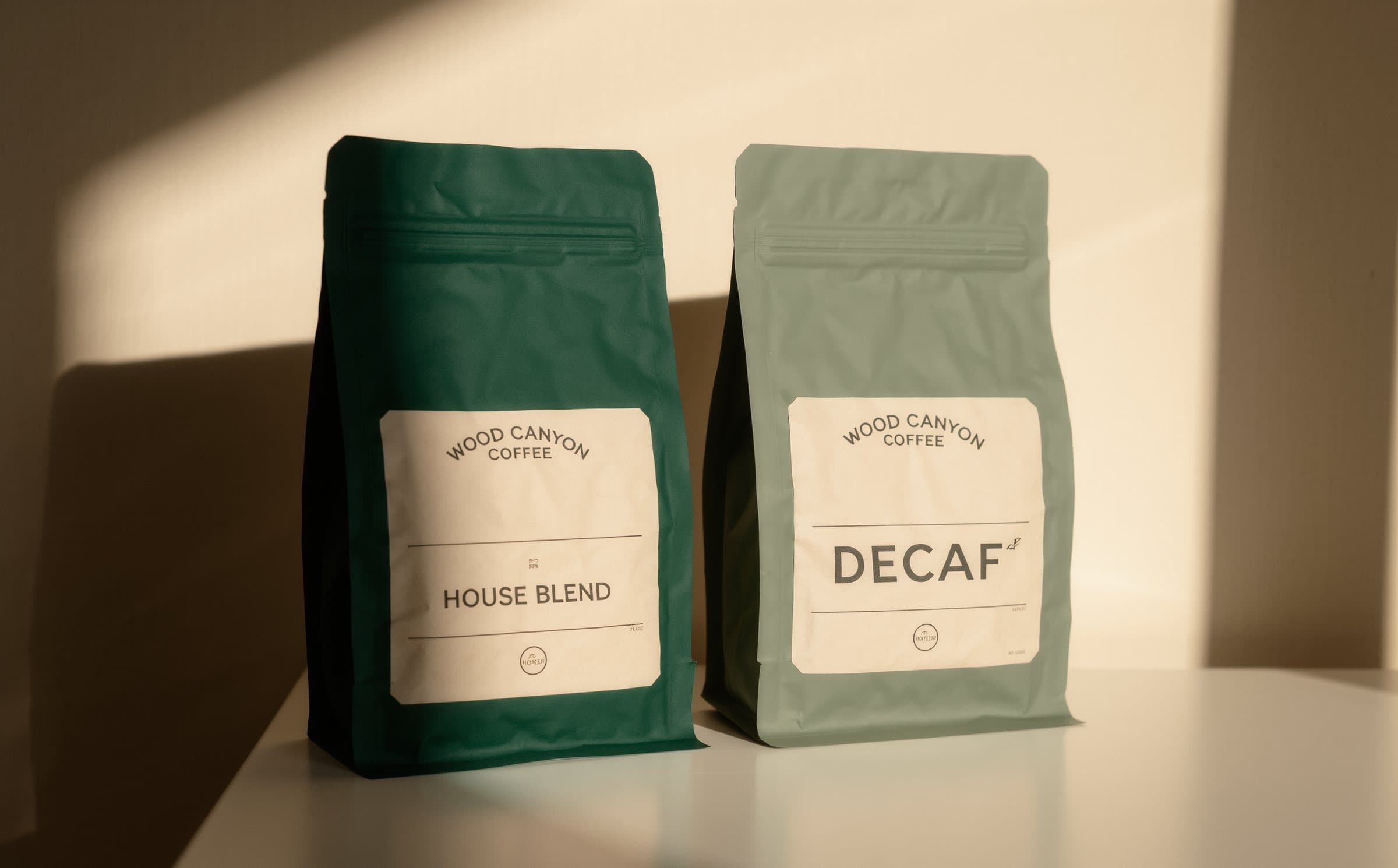House Blend in a deep green bag beside Decaf in a sage bag, in morning light.